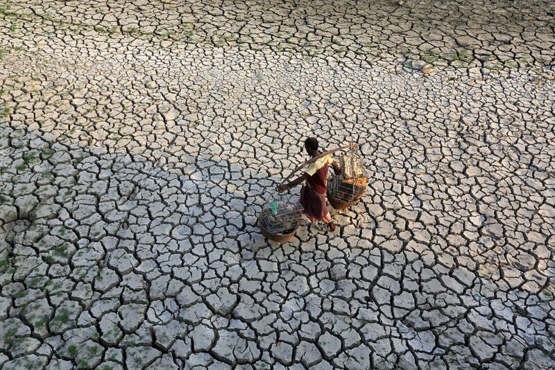J0PGXE A vendor passes through a drought-parched field at Beraid under Dhaka?s Bhatara. Bangladesh