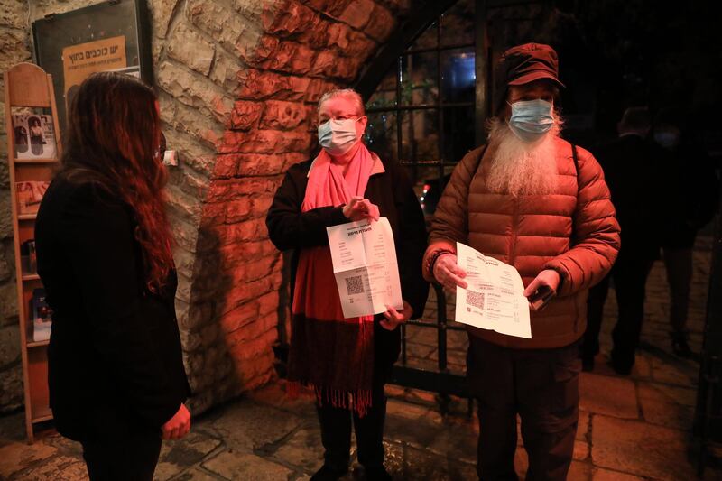 People present their coronavirus vaccination certificate at the entrance to the Khan Theatre in Jerusalem.