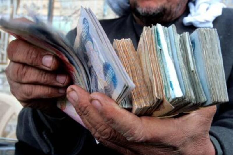 TO GO WITH STORY BY TAHAR MAJDOUB: An Iraqi money changer holds a handful of Iraqi currency in central Baghdad on February 16, 2008. Baghdad's Al-Harithiya market is known for money changing since the mid-1990s when if turned from a black market to an 'official' outdoor exchange venue in the Iraqi capital.   AFP PHOTO / SABAH ARAR