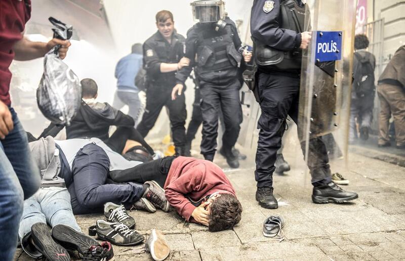 Injured protesters lie on the ground as Turkish riot police officers fire tear gas to disperse demonstrators gathered on the central Istoklal avenue near Taksim square in Istanbul. Bulent Kilic / AFP