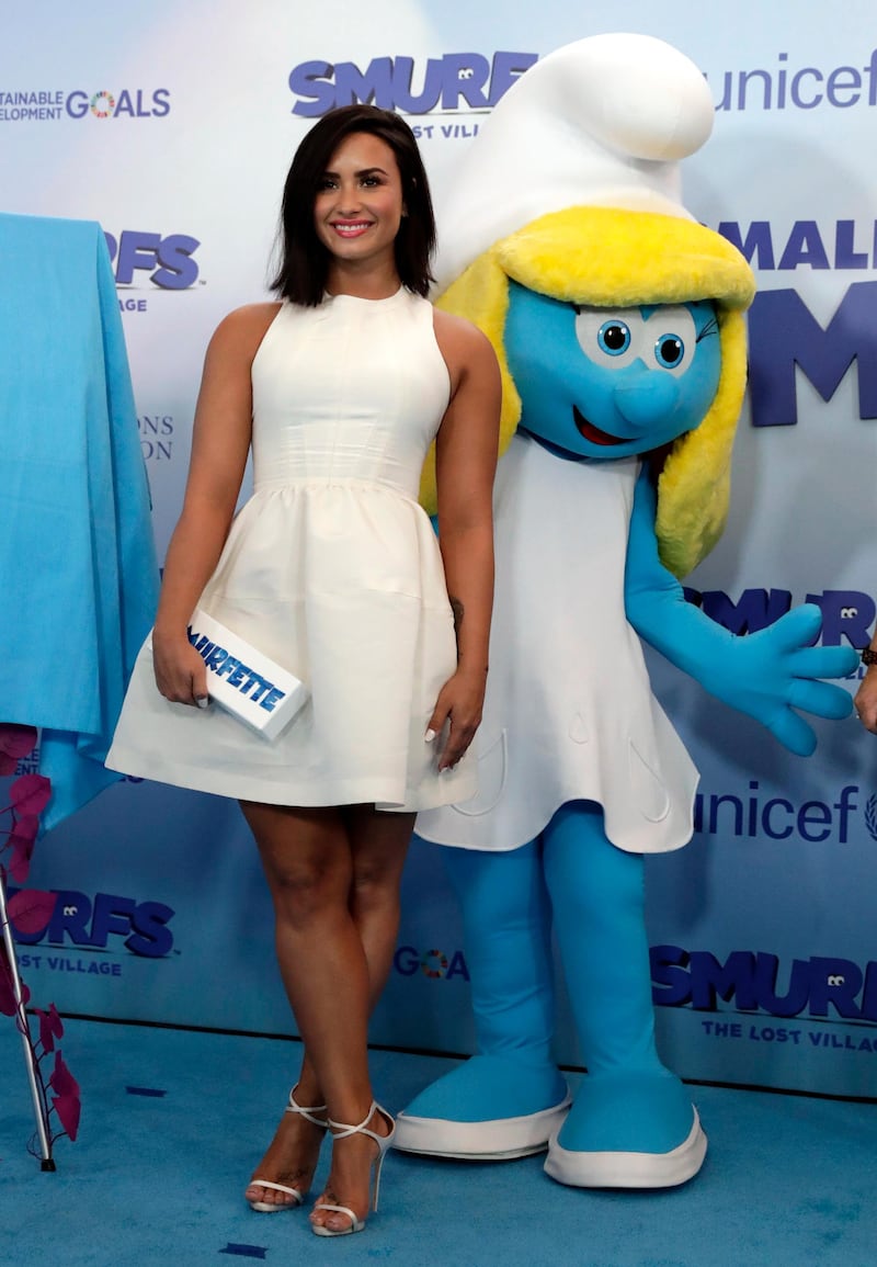 epa05856448 US singer/actress Demi Lovato smiles in front of Smurfette at the International Day of Happiness in conjunction with 'Smurfs: The Lost Village' at United Nations headquarters in New York, New York, USA, 18 March 2017. Lovato is the dubbing voice of the character 'Smurfette' in the upcoming movie 'Smurfs: The Lost Village'.  EPA/JASON SZENES