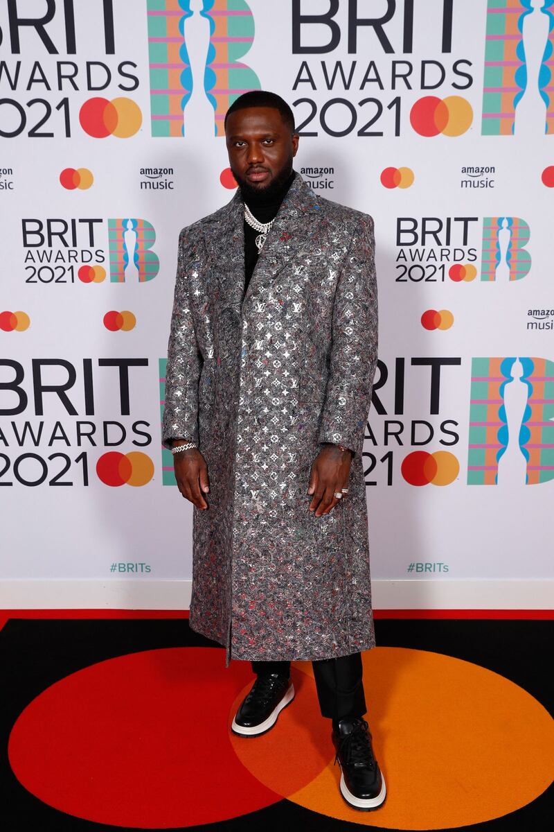 Headie One poses on the Brits red carpet in a metallic silver overcoat. AFP