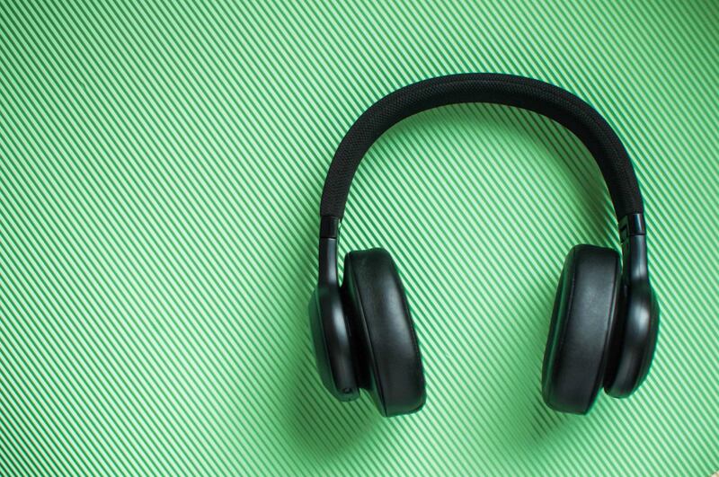 A flat lay of black pair of headphone on a green background. Getty Images