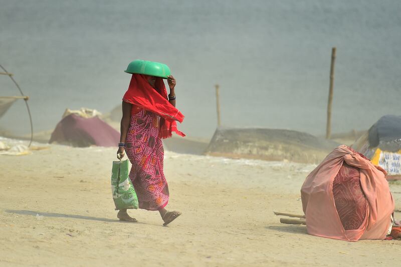 A woman covers her head with a plastic tub near Sangam, the confluence of the Ganges, Yamuna and mythical Saraswati rivers. AFP