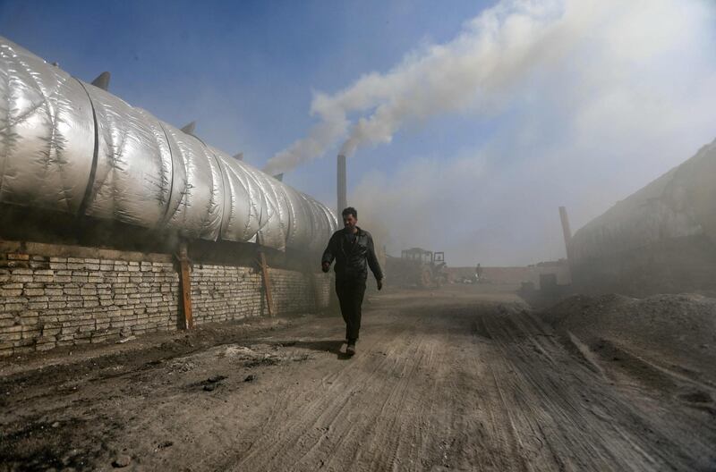 A man walks near installations at a makeshift oil refinery near Tarhin, in Aleppo, Syria. Amateur refineries appeared following a drastic decline in production at professional refineries in the war-torn country. AFP