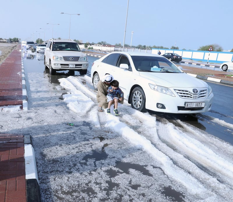 Hail collects on the sides of the roads in Umm Al Quwain in March 2019 - to the joy of this family. Wam