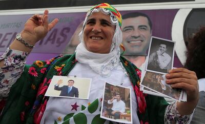 A supporter of Turkey's main pro-Kurdish Peoples' Democratic Party (HDP) holds pictures of their jailed former leader and presidential candidate Selahattin Demirtas during a campaign event in Istanbul, Turkey May 25, 2018. REUTERS/Huseyin Aldemir       NO RESALES. NO ARCHIVES.