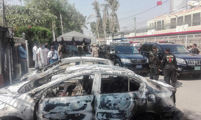 Pakistani security personnel stand next to burnt vehicles in front of the Chinese consulate in Karachi. AFP