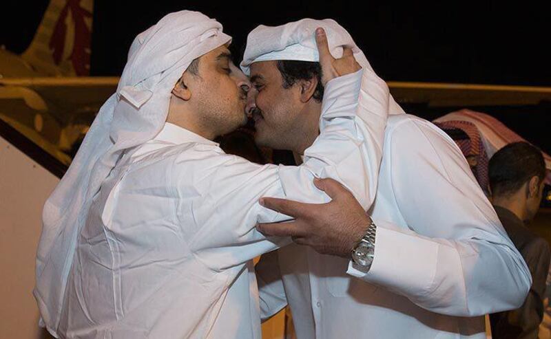 Emir of Qatar, Sheikh Tamim Bin Hamad Al Thani, right, receives a released Qatari hostage at the Doha airport. Qatar News Agency via AP