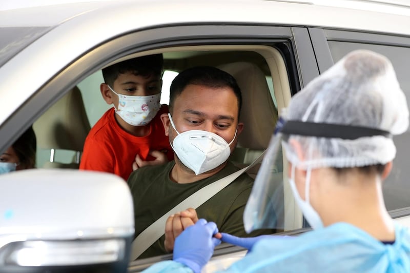 A healthcare worker performs a coronavirus test at a drive-through centre in Abu Dhabi. Chris Whiteoak / The National