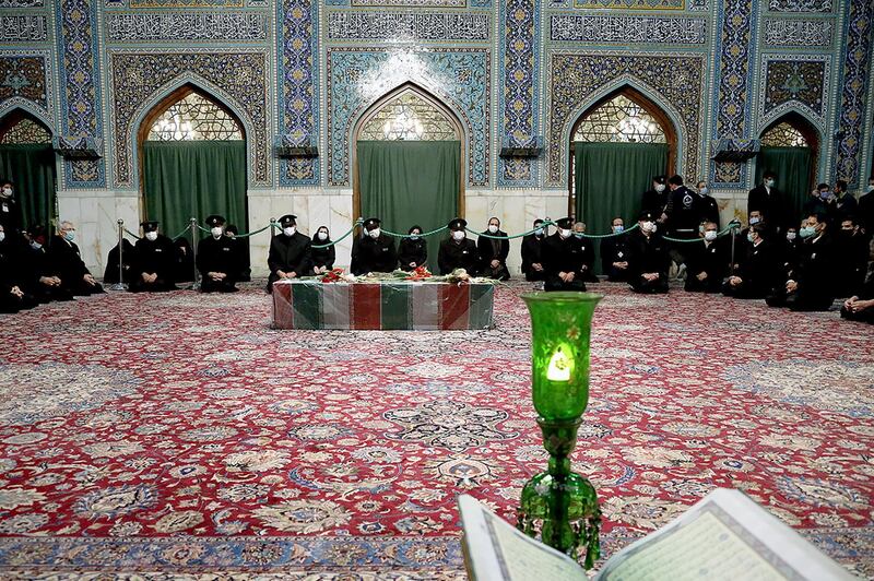 Servants of the holy shrine of Imam Reza sit near the coffin of Iranian nuclear scientist Mohsen Fakhrizadeh in Mashhad, Iran. WANA via REUTERS