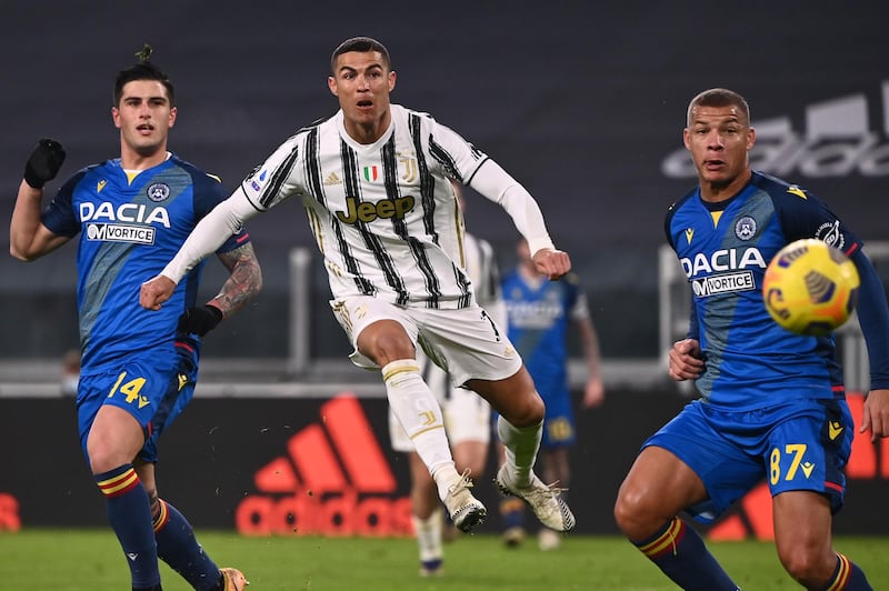 Juventus' Portuguese forward Cristiano Ronaldo (C) shoots to score the opening goal despite Udinese's Italian defender Kevin Bonifazi (L) and Udinese's French defender Sebastian De Maio during the Italian Serie A football match Juventus vs Udinese on January 3, 2021 at the Juventus stadium in Turin. (Photo by Marco BERTORELLO / AFP)