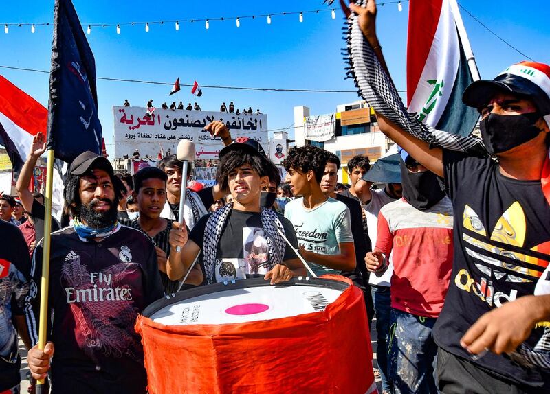 Iraqi protesters wave national flags as they take to the streets to mark the first anniversary of a massive anti-government movement demanding the ouster of the entire ruling class accused of corruption, in the southern city of Nasiriyah in Dhi Qar province.  AFP