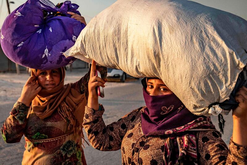 Civilians carry their belongings over their head as they flee amid Turkish bombardment on Syria's northeastern town of Ras Al Ain. AFP