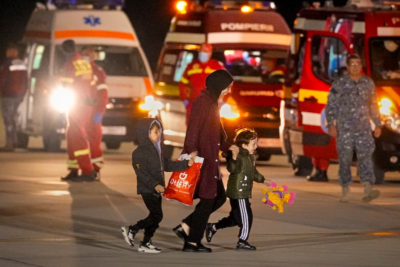 A woman and two children evacuated from Gaza walk on the tarmac at the Baza 90 air force base in Otopeni, Romania, after arriving from Egypt. AP