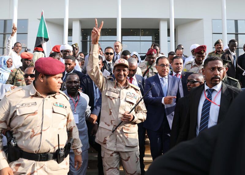 epa07778235 Sudan's General and Vice President of Sudanese Transitional Military Council, Mohamed Hamdan Dagalo (C) flashes a victory sign as he leaves after signing a power sharing agreement with the opposition, in Khartoum, Sudan, 17 August 2019. According to reports, Sudan's Military council and opposition signed the power sharing agreement that has been negotiated for many months. The agreement sets up a sovereign council made of five generals and six civilians, to rule the country until general elections. Protests had erupted in Sudan at the end of 2018, culminating in a long sit-in outside the army headquarters which ended with more than one hundred people being killed and others injured. Sudanese President Omar Hassan al-Bashir stepped down on 11 April 2019.  EPA/STR