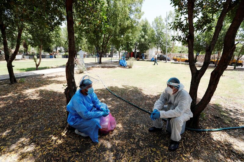 Healthcare workers take a break from their work and sit at a Park during testing for the coronavirus disease (COVID-19) in Sadr city, district of Baghdad, Iraq May 21, 2020. REUTERS/Thaier Al-Sudani