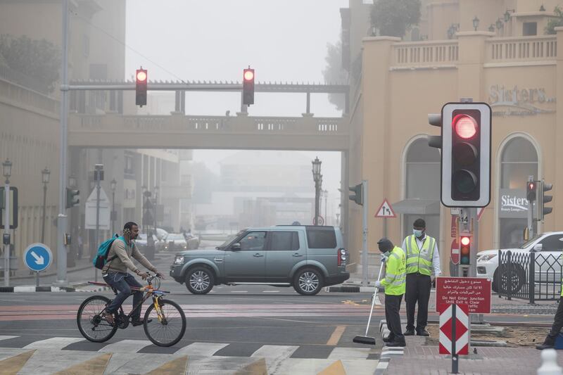 DUBAI, UNITED ARAB EMIRATES. 24 DECEMBER 2017. Heavy morning fog envelopes the city. Cleaners work on an intersection in the Marina. (Photo: Antonie Robertson/The National) Journalist: None. Section: National.