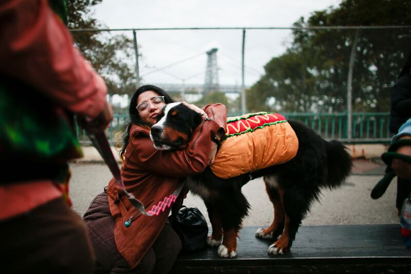 A woman hugs a dog in a hot dog costume during the parade. AFP