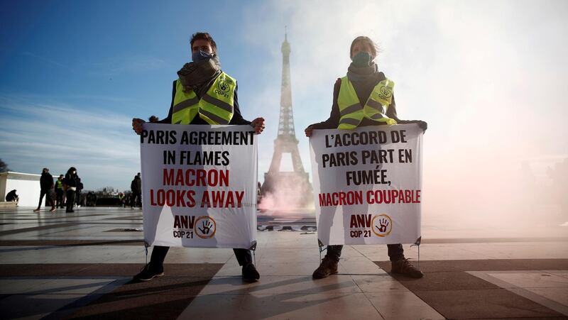 FILE PHOTO: Climate activists demonstrate in front of the Eiffel tower to mark the fifth anniversary of the 2015 United Nations Paris Agreement on climate change, in Paris, France, December 10, 2020. The slogan reads "Paris Agreement in flames, Macron looks away". REUTERS/Benoit Tessier/File Photo