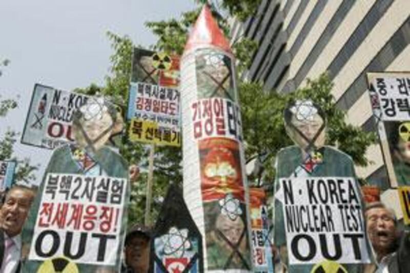 Anti-North Korea protesters shout slogans as they hold portraits of North Korean leader Kim Jong-il and mock North Korean missiles during a rally denouncing its nuclear threat in front of the U.S. embassy in Seoul today.