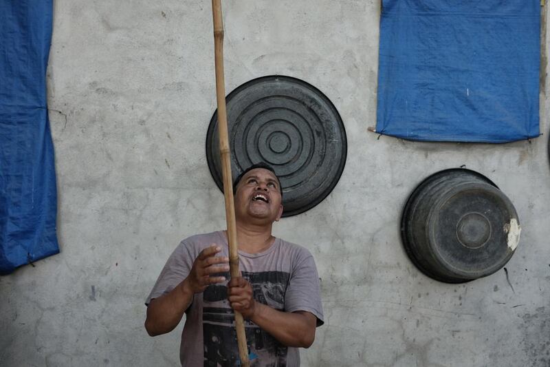 Ermando uses a bamboo pole to prize a guava from a tree. He has joined a programme called AMMA — an acronym that translated from Tagalog means ‘A father who excels in nurturing his child’. It teaches everything from how to connect and talk to children to financial literacy.