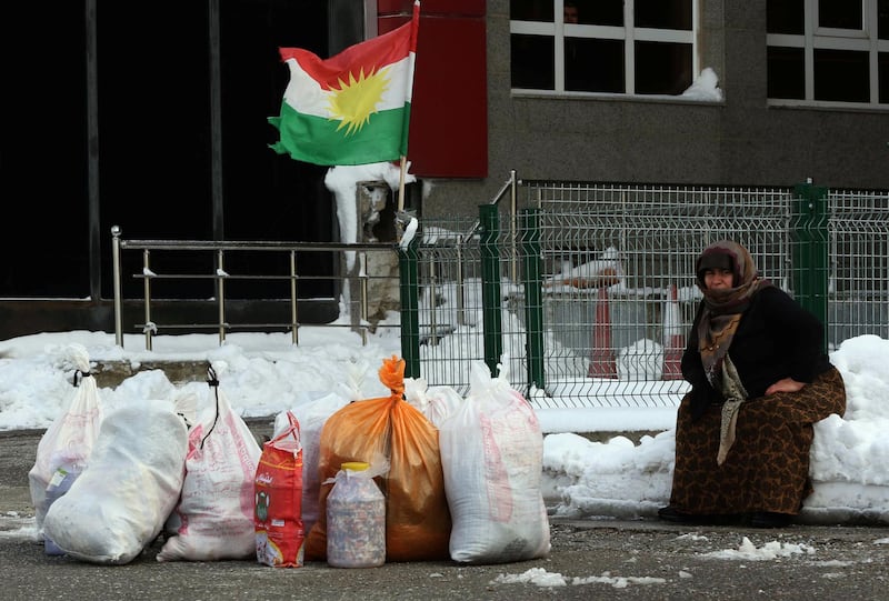 A woman sits on the snow with Kurdish flags in the background at the Iran-Iraq border crossing of Haji Omran on January 3, 2018, one day after two border posts were reopened between Iraqi Kurdistan and the Islamic republic. - The borders had been closed in response to an independence vote rejected by Baghdad and neighbouring countries last year.
The Iranian consulate in the Kurdish autonomous region's capital Arbil announced the Parwezkhan and Haji Omran posts were beginning work again as of January 3 which makes all crossings on the border between Iran and Iraqi Kurdistan up and running after a third post at Bashmaq started working again in October 2017. (Photo by SAFIN HAMED / AFP)