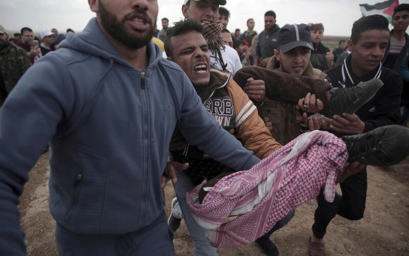 Palestinian protesters carry a wounded man who was shot by Israeli troops during a demonstration near the Gaza Strip border with Israel in eastern Gaza City on March 30, 2018. Khalil Hamra / AP Photo