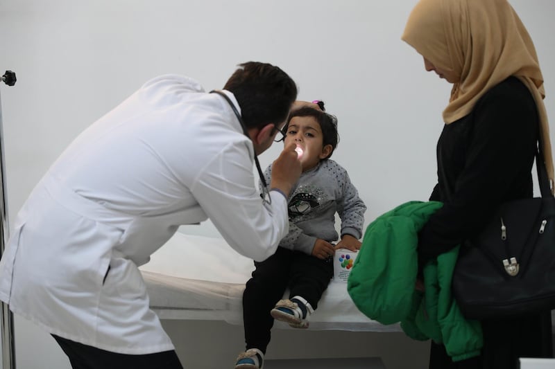This picture taken on February 22, 2018 shows four-year-old Ahed examined by doctor Mohammad Khattab at a Migrant Health Center in Ankara on February 22 2018.  
The Ankara centre's medical team is partly made up of Syrian refugees. / AFP PHOTO / ADEM ALTAN