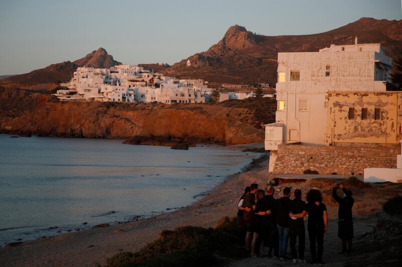 Tourists pose for a photograph as the sun sets in Chora, on the Aegean island of Naxos, Greece,. AP Photo/Thanassis Stavrakis)