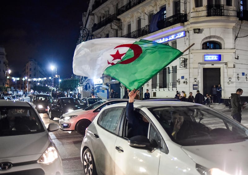 An Algerian waves a national flag from out the window of a car during a demonstration in the centre of the capital Algiers on March 11, 2019, after President Abdelaziz Bouteflika announced his withdrawal from a bid to win another term in office and postponed an April 18 election, following weeks of protests against his candidacy.  Bouteflika, in a message carried by national news agency APS, said the presidential poll would follow a national conference on political and constitutional reform to be drawn up by the end of 2019. / AFP / RYAD KRAMDI                        

