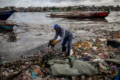 A member of the River Warriors gathers trash from the heavily polluted Pasig River in Manila. Reuters
