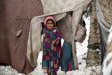 A young Afghan refugee peers from her temporary home after a snowstorm at a camp on the outskirts of Kabul, Afghanistan. AP, File