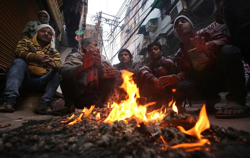 Indian men warm themselves near a fire during a cold winter morning in New Delhi. EPA