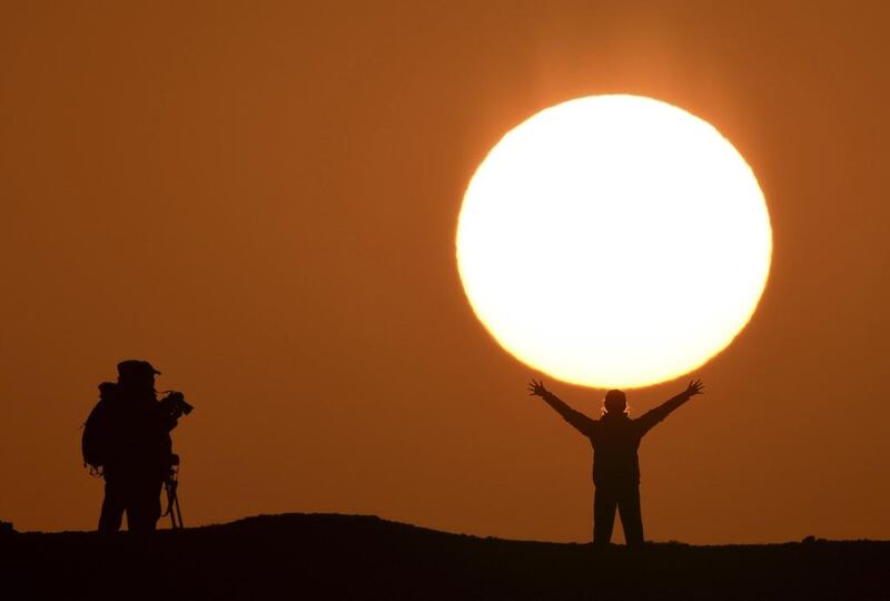 A tourist poses for photographs in front of the rising sun in Bayingolin Mongol Autonomous Prefecture, Xinjiang Uighur Autonomous Region, China. Reuters