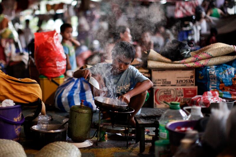 A boy cooks for his family at a typhoon evacuation centre in Navotas City, north of metro Manila. Reuters