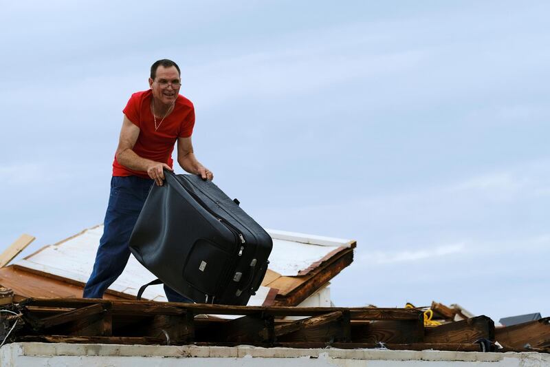 A man throws a suitcase from the roof of his home in the aftermath of Hurricane Dorian on the Great Abaco island town of Marsh Harbour, Bahamas.  Reuters