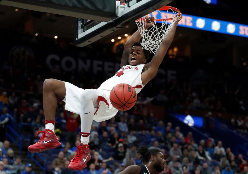 Arkansas' Daryl Macon hangs from the rim after dunking the ball an NCAA college basketball game against South Carolina. Jeff Roberson / AP Photo