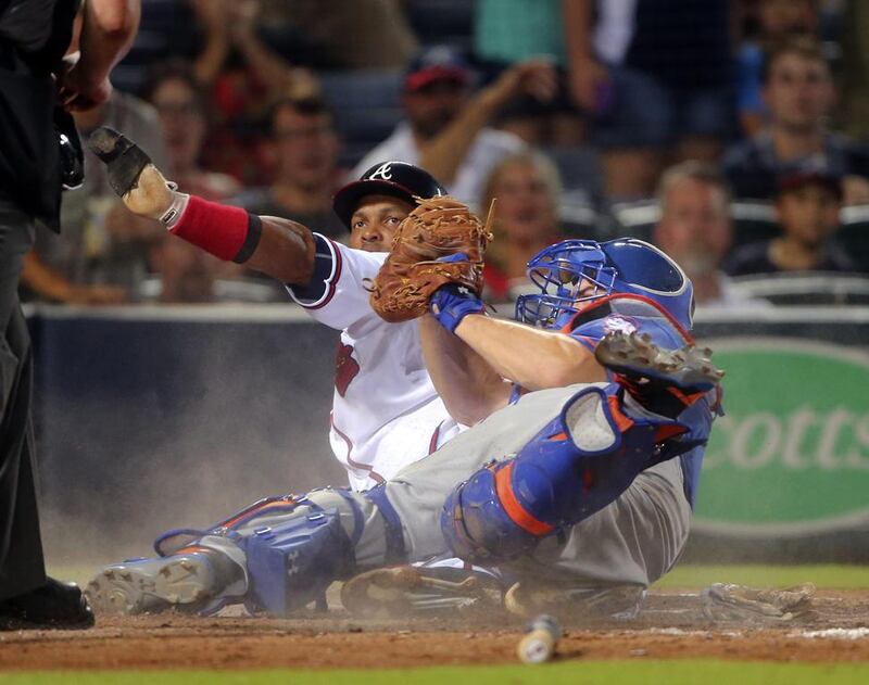 Emilio Bonifacio of the Atlanta Braves, centre left, is tagged out by New York Mets catcher Travis d’Arnaud, centre right, during their baseball game. John Bazemore / AP Photo