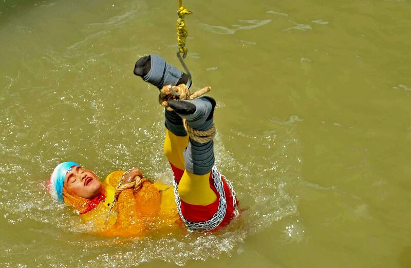 In this photo taken on June 16, 2019 Indian stuntman Chanchal Lahiri, known by his stage name "Jadugar Mandrake", is lowered into the Ganges river, while tied up with steel chains and ropes, in Kolkata. An Indian magician who went missing after being lowered into a river tied up in chains and ropes in a Houdini-inspired stunt is feared drowned, police said June 17.
 / AFP / STR
