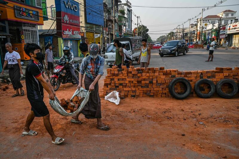 Protesters carry bricks to construct a makeshift barricade to deter security forces, during demonstrations against the military coup, in Yangon Myanmar. AFP