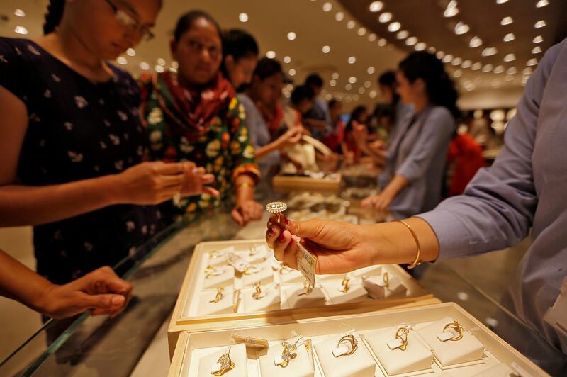 FILE PHOTO: A sales person shows a gold ring to customers at a jewellery showroom during Dhanteras, a Hindu festival associated with Lakshmi, the goddess of wealth, in Ahmedabad, India, October 28, 2016. REUTERS/Amit Dave - S1AEUJOCBTAB/File Photo