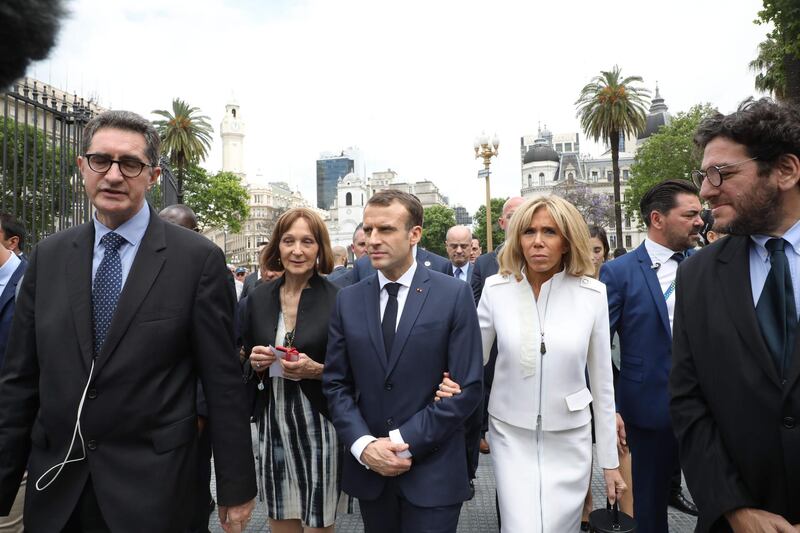 France's President Emmanuel Macron (C) and France's First Lady Brigitte Macron visit Plaza de Mayo along with the president of Argentina's National Commission of Monuments, Places and Historical Heritage Teresa de Anchorena (2nd L), in Buenos Aires on November 29, 2018. Macron arrived on the eve for a two-day G20 summit beginning on November 30 likely to be dominated by simmering international tensions over trade. In an interview with Argentine daily La Nacion, he warned against the risk of "a destructive trade war for all" emanating from the G20 discussions.  - 
 / AFP / Ludovic MARIN / POOL
