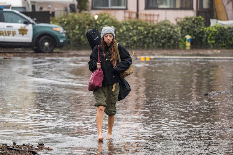 Naia Skogerson leaves her house as floodwaters rise in the Rio Del Mar neighbourhood of Aptos. AP