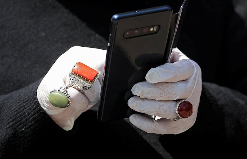 A man holds a mobile as he wears rings over gloves in Sidon, Lebanon. Reuters