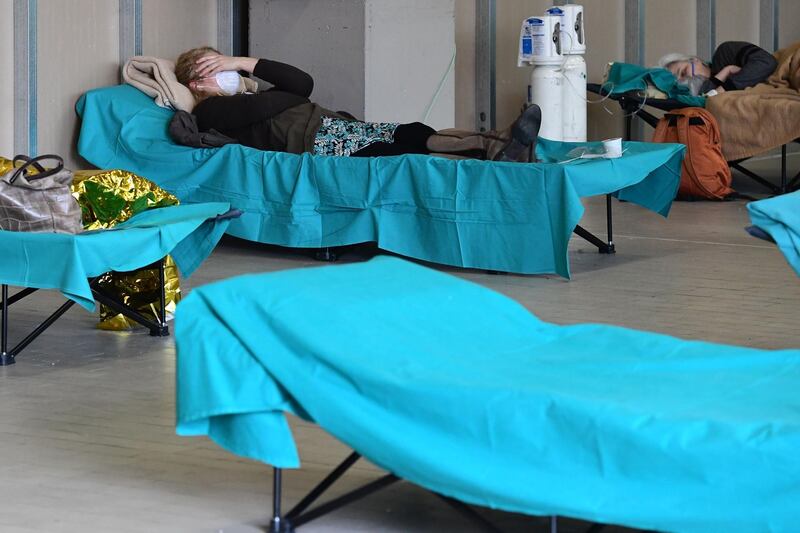 Patients lie in bed at a temporary emergency structure set up outside the accident and emergency department, where any new arrivals presenting suspect new coronavirus symptoms will be tested, at the Brescia hospital, Lombardy, on March 13, 2020. / AFP / Miguel MEDINA
