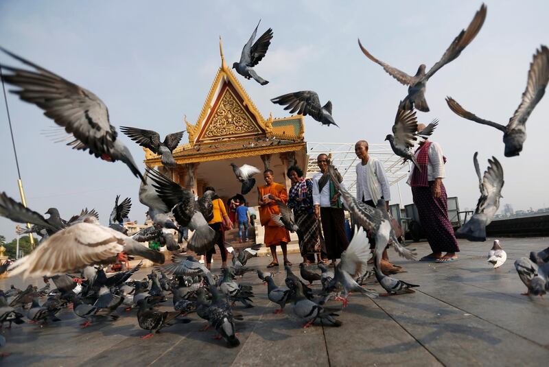 People feed birds with corn in front of the Royal Palace in central Phnom Penh, Cambodia. Samrang Pring / Reuters