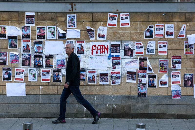 A man walks past images of Israeli hostages snatched by the Palestinian militant group Hamas last week in a surprise attack into Israel, plastered on a wall outside the Ministry of Defence in Tel Aviv. AFP