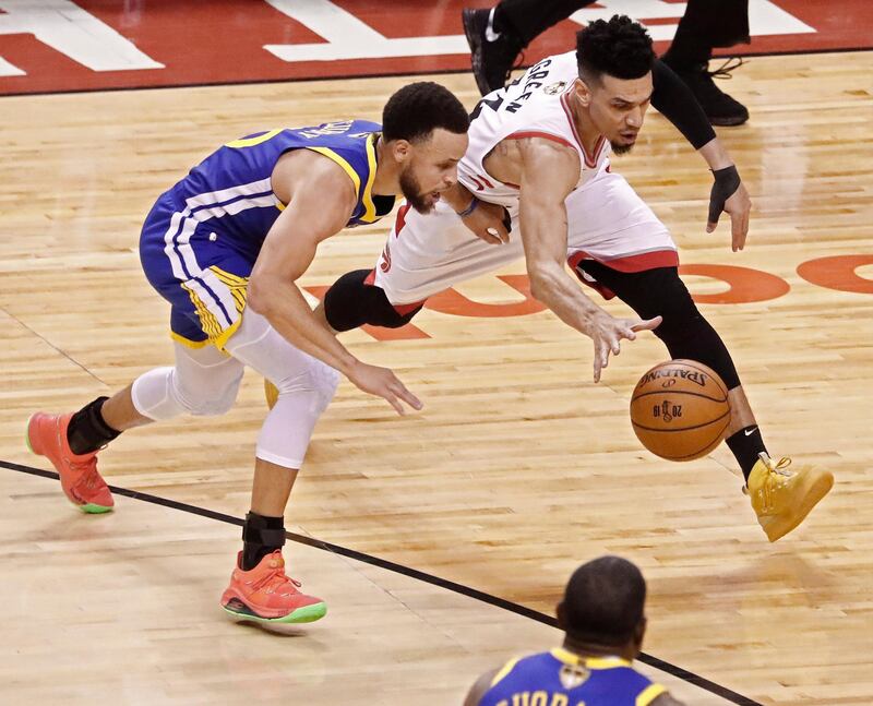 Toronto Raptors player Danny Green goes for a loose ball against Golden State Warriors player Stephen Curry.