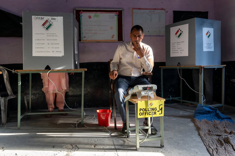 A polling official looks on as a woman casts her vote in Dharamshala. AP Photo